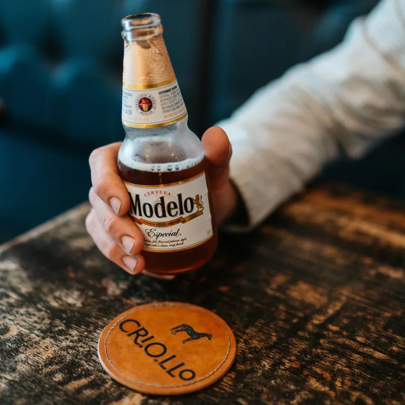 A cold beer set on a Criollo leather coaster