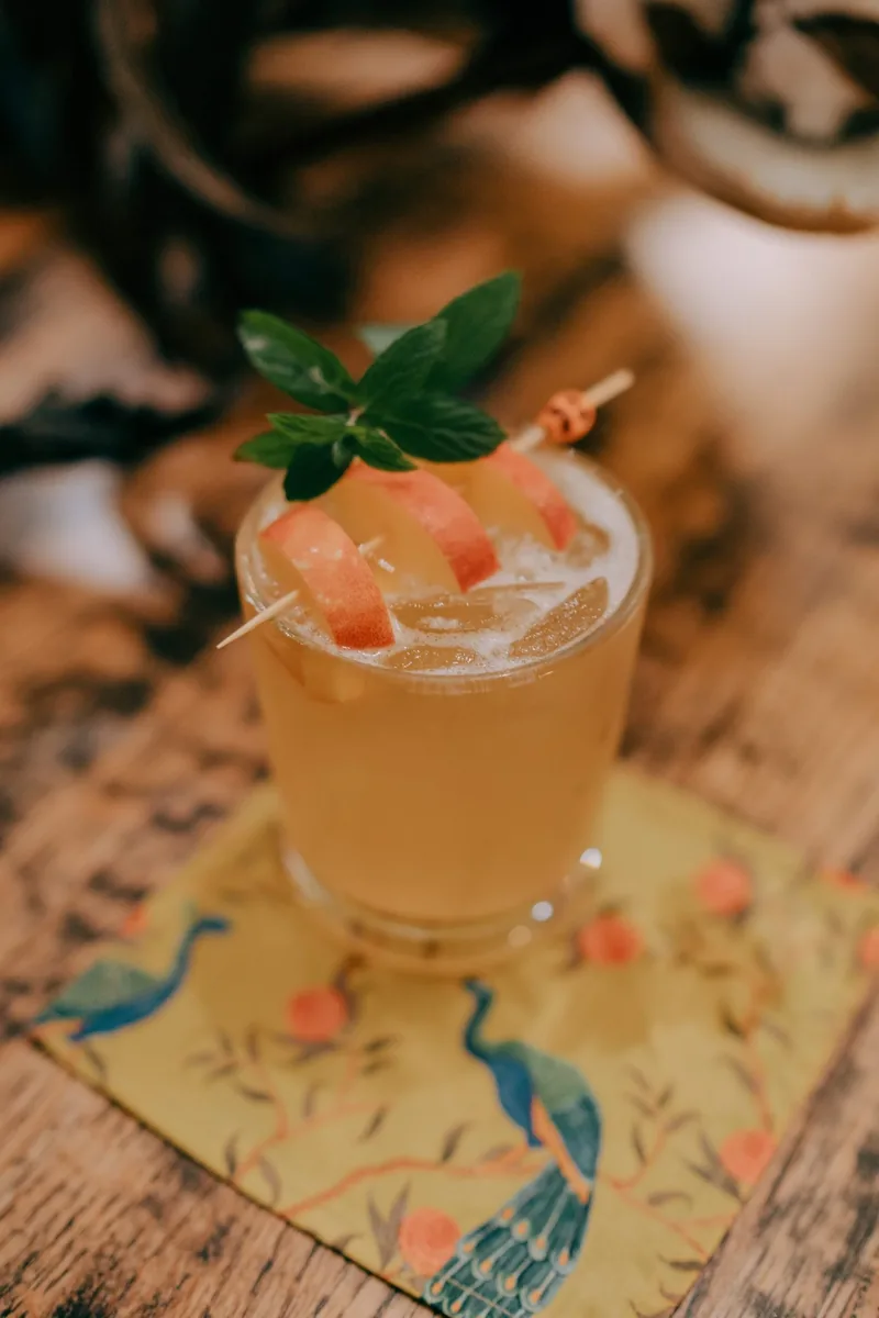 A garnished cocktail on a printed mat at Criollo