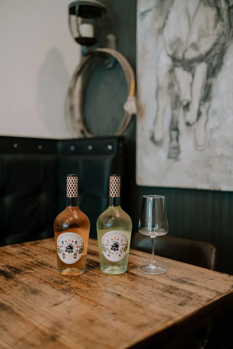 A framed horse drawing above a table set with wine